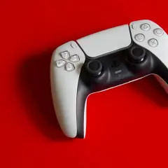 Biały kontroler DualSense na czerwonym tle. Idealny do gier na PS5, a dzięki DS4Windows sprawdzi się też na PC.