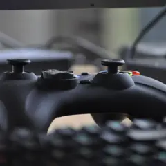 Czarny kontroler do gier leży na klawiaturze, gotowy do akcji. W tle widać monitor, jakby tworzył **steam cloud** dla wirtualnych światów.