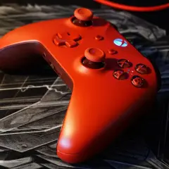 Czerwony kontroler Xbox na czarnej podkładce z motywem graficznym. Idealny do gry z nowym dlc.