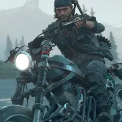 Mężczyzna w czapce i kamizelce jedzie motocyklem w deszczu, w tle las i góry. To scena z gry Days Gone 2.