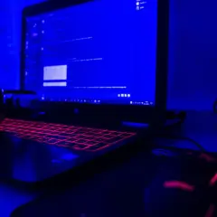 Gamingowy laptop z podświetlaną klawiaturą i słuchawkami, gotowy do tworzenia rankingu laptopów gamingowych.