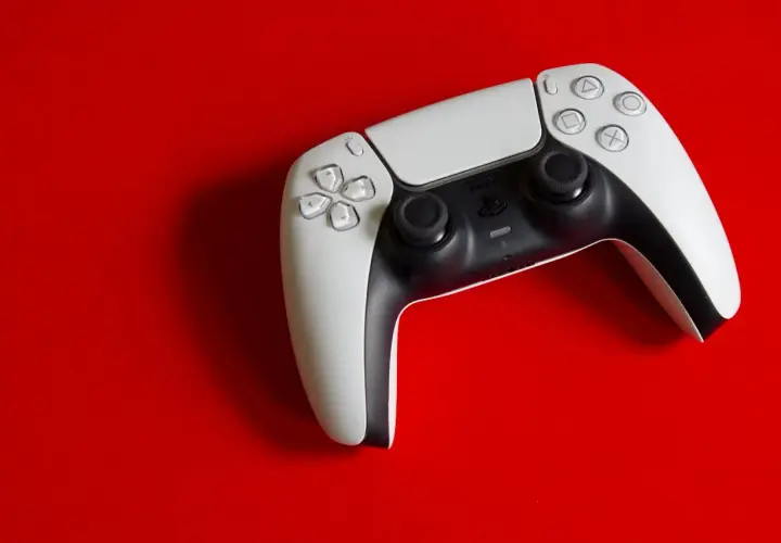 Biały kontroler DualSense na czerwonym tle. Idealny do gier na PS5, a dzięki DS4Windows sprawdzi się też na PC.