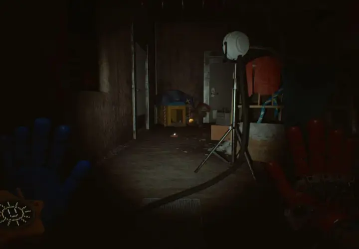 Ręce gracza w grze Poppy Playtime Chapter 5, w mrocznym korytarzu fabryki zabawek.