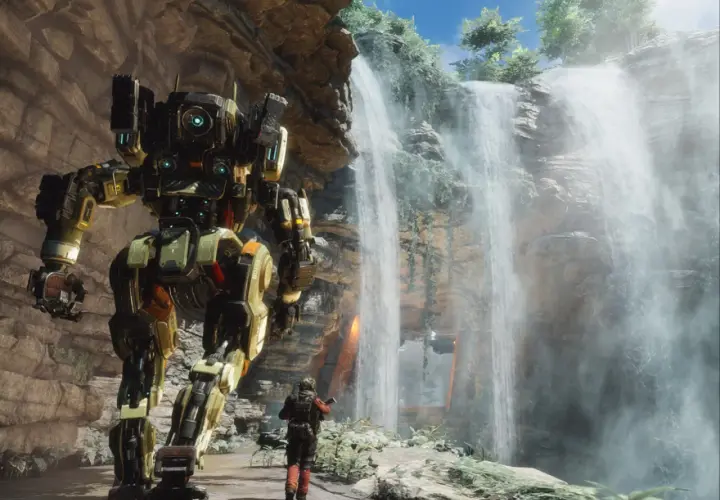 Potężny mech z gry Titanfall 3 stoi obok wodospadu, a pilot w skafandrze bojowym obserwuje go.
