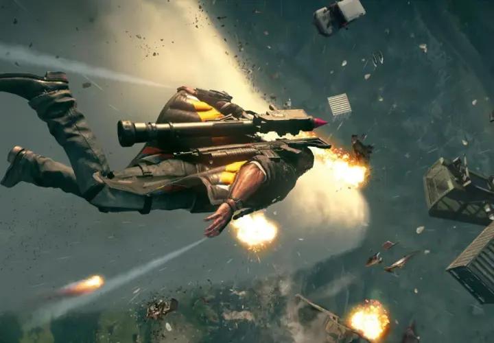 Rico z Just Cause 5 w akcji, lecący w powietrzu z wyrzutnią rakiet, otoczony eksplozjami i spadającymi obiektami.