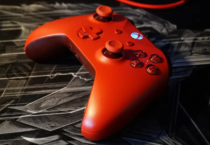 Czerwony kontroler Xbox na czarnej podkładce z motywem graficznym. Idealny do gry z nowym dlc.