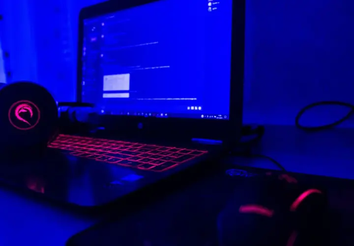 Gamingowy laptop z podświetlaną klawiaturą i słuchawkami, gotowy do tworzenia rankingu laptopów gamingowych.