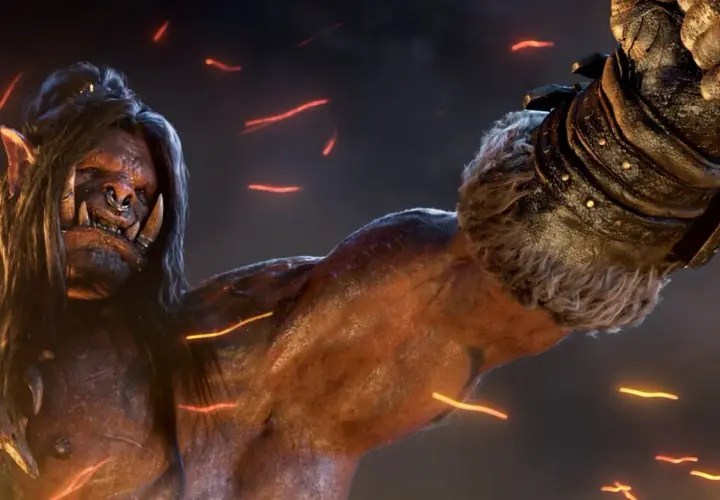 Groźny ork z World of Warcraft: Warlords of Draenor, z długimi włosami i kolczykiem w nosie, unosi pięść.