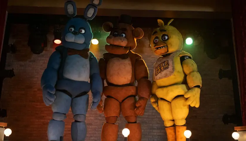 Trzej animatronicy z filmu FNAF: Bonnie, Freddy i Chica stoją na scenie.
