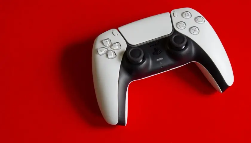 Biały kontroler DualSense na czerwonym tle. Idealny do gier na PS5, a dzięki DS4Windows sprawdzi się też na PC.