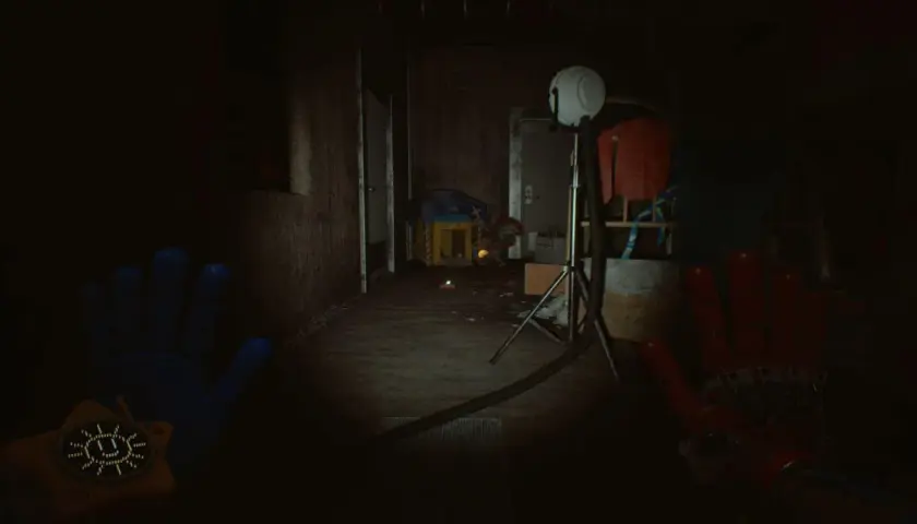 Ręce gracza w grze Poppy Playtime Chapter 5, w mrocznym korytarzu fabryki zabawek.
