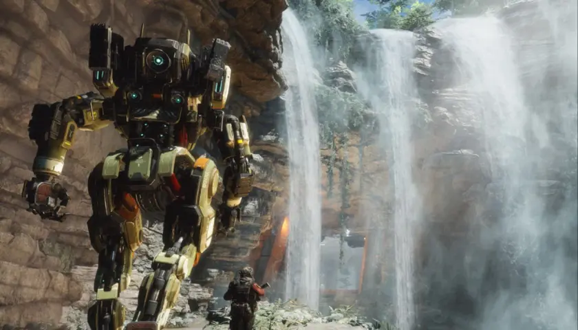 Potężny mech z gry Titanfall 3 stoi obok wodospadu, a pilot w skafandrze bojowym obserwuje go.