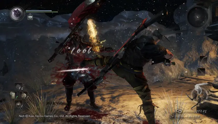 Intensywna walka w Nioh 2. Wojownik w czerwonej zbroi otrzymuje cios, z jego ciała tryska krew.