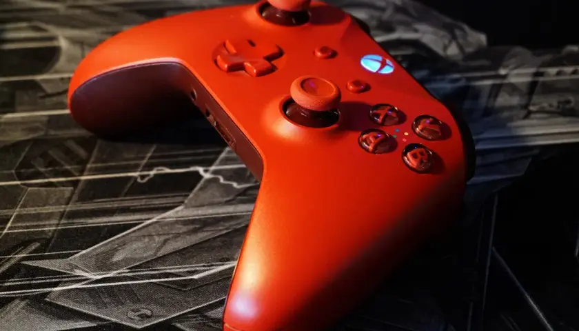 Czerwony kontroler Xbox na czarnej podkładce z motywem graficznym. Idealny do gry z nowym dlc.