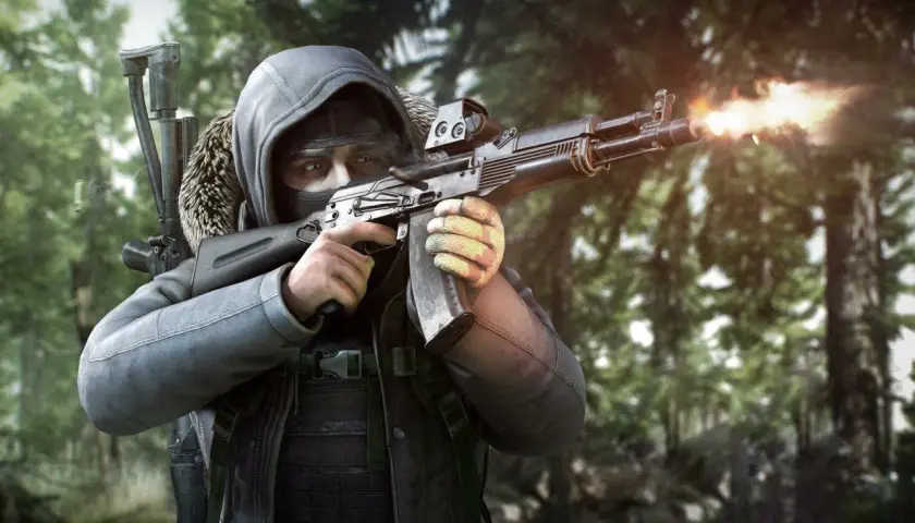 Gracz w masce i kapturze strzela z karabinu w lesie. To scena z gry Escape from Tarkov, gdzie cena przetrwania jest wysoka.