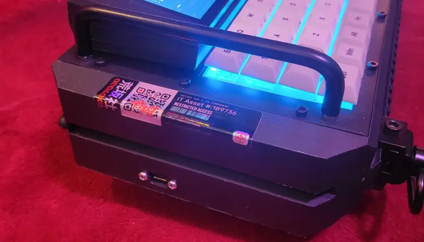 Cyberdeck z podświetlaną klawiaturą i ekranem, z naklejką "Restricted Access".