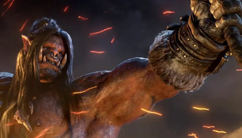 Groźny ork z World of Warcraft: Warlords of Draenor, z długimi włosami i kolczykiem w nosie, unosi pięść.