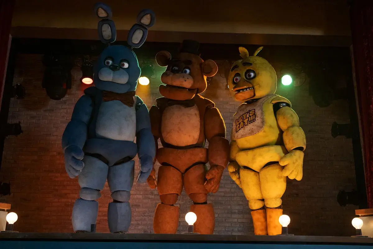 Trzej animatronicy z filmu FNAF: Bonnie, Freddy i Chica stoją na scenie.