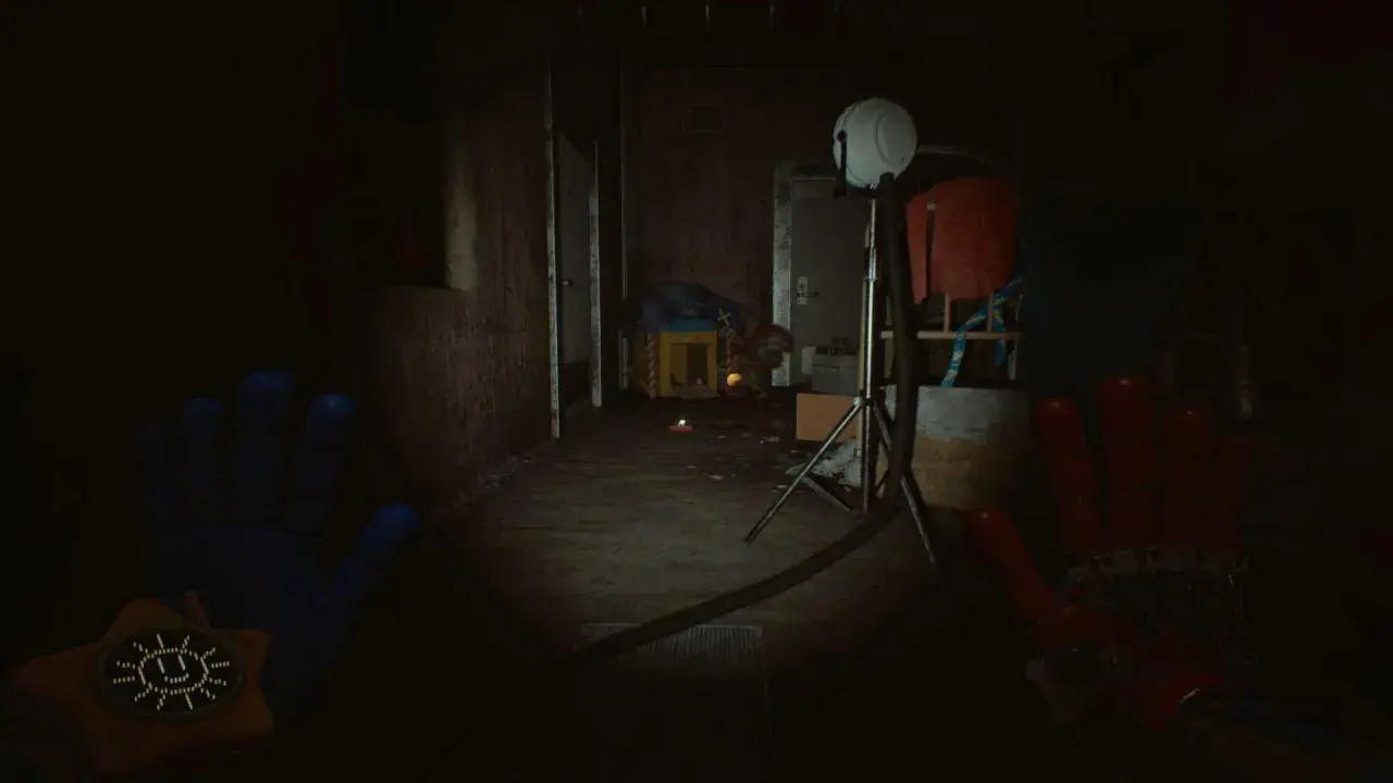 Ręce gracza w grze Poppy Playtime Chapter 5, w mrocznym korytarzu fabryki zabawek.