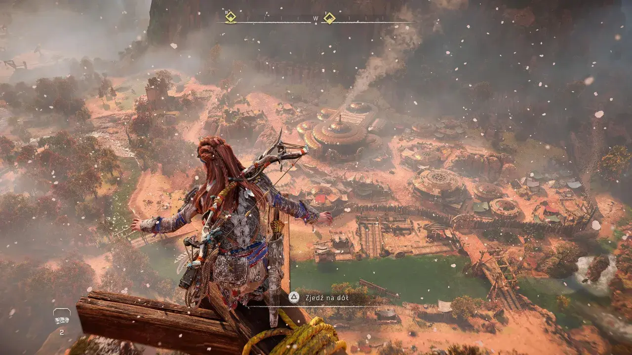 Aloy z Horizon Zero Dawn 2 spogląda na osadę z góry. W tle widać górzysty krajobraz i mgłę.