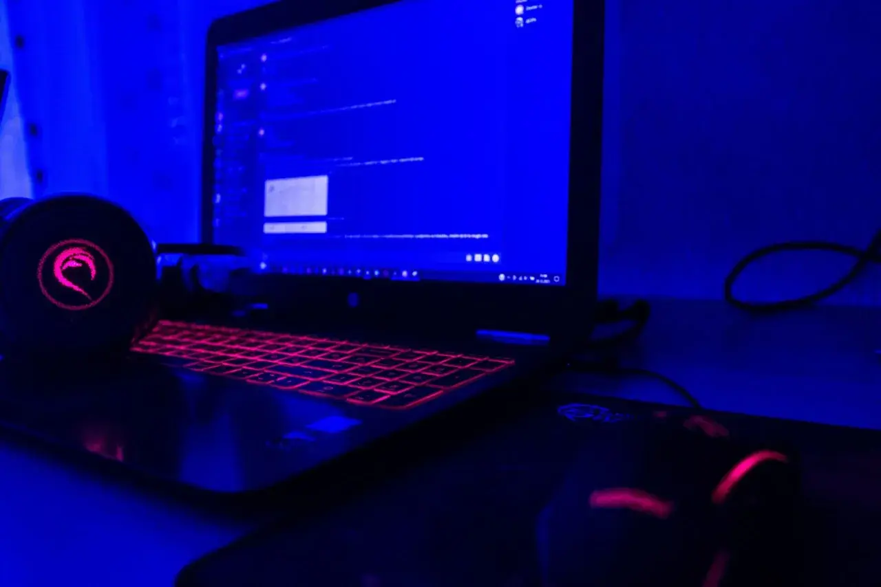 Gamingowy laptop z podświetlaną klawiaturą i słuchawkami, gotowy do tworzenia rankingu laptopów gamingowych.