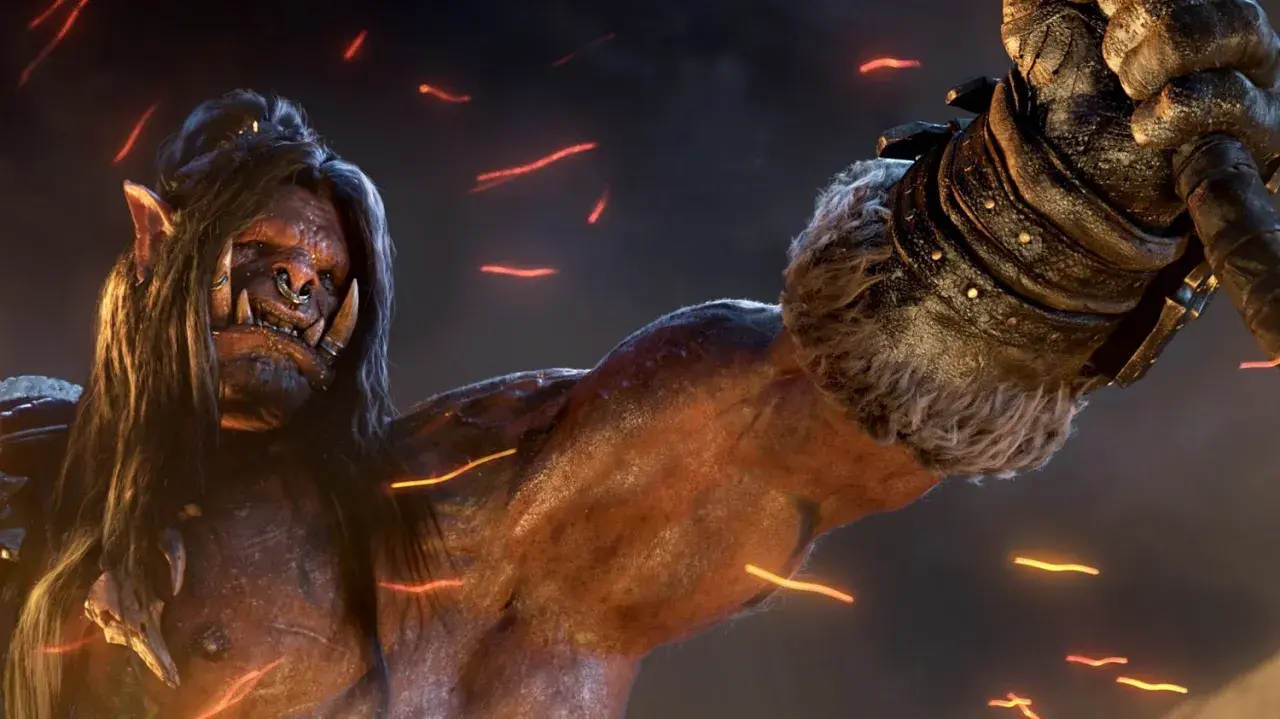 Groźny ork z World of Warcraft: Warlords of Draenor, z długimi włosami i kolczykiem w nosie, unosi pięść.