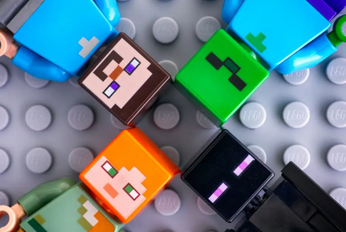 Postacie z Minecrafta, najpopularniejszej gry na świecie, na szarej płytce LEGO. Steve, Alex, Creeper i Enderman w wersji klockowej.